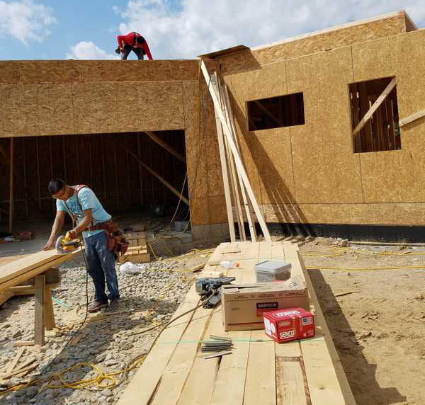 Worker Cutting Wood in House Building Site