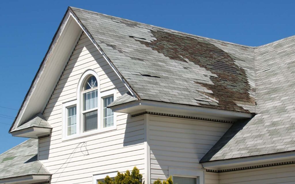 Visible signs of roof repair needs including water stains and damaged shingles